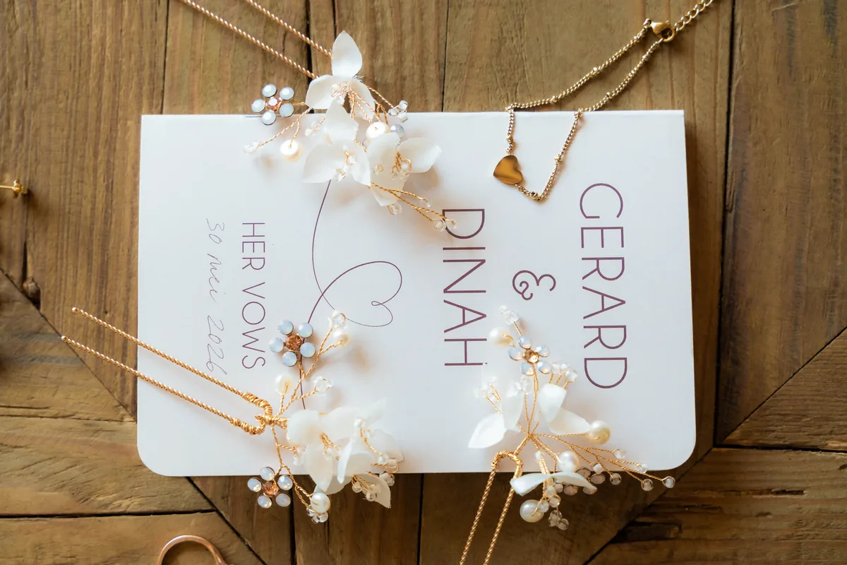 Het boekje met Dinahs geloften, met de namen Gerard en Dinah, tussen haarsieraden en kettingen op een houten ondergrond
