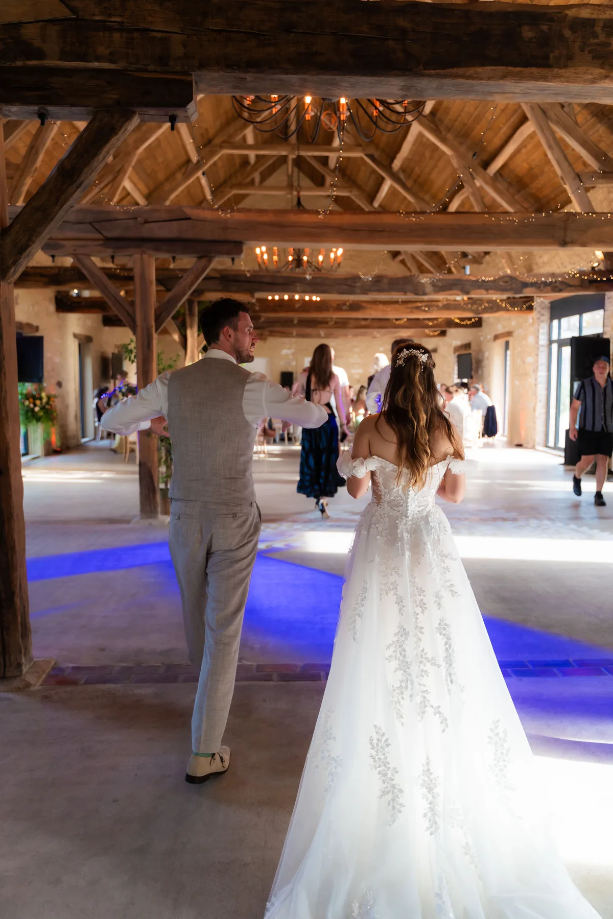 Gerard en Dinah lopen een grote zaal binnen met houten dakspanten, kroonluchters en natuurstenen muren