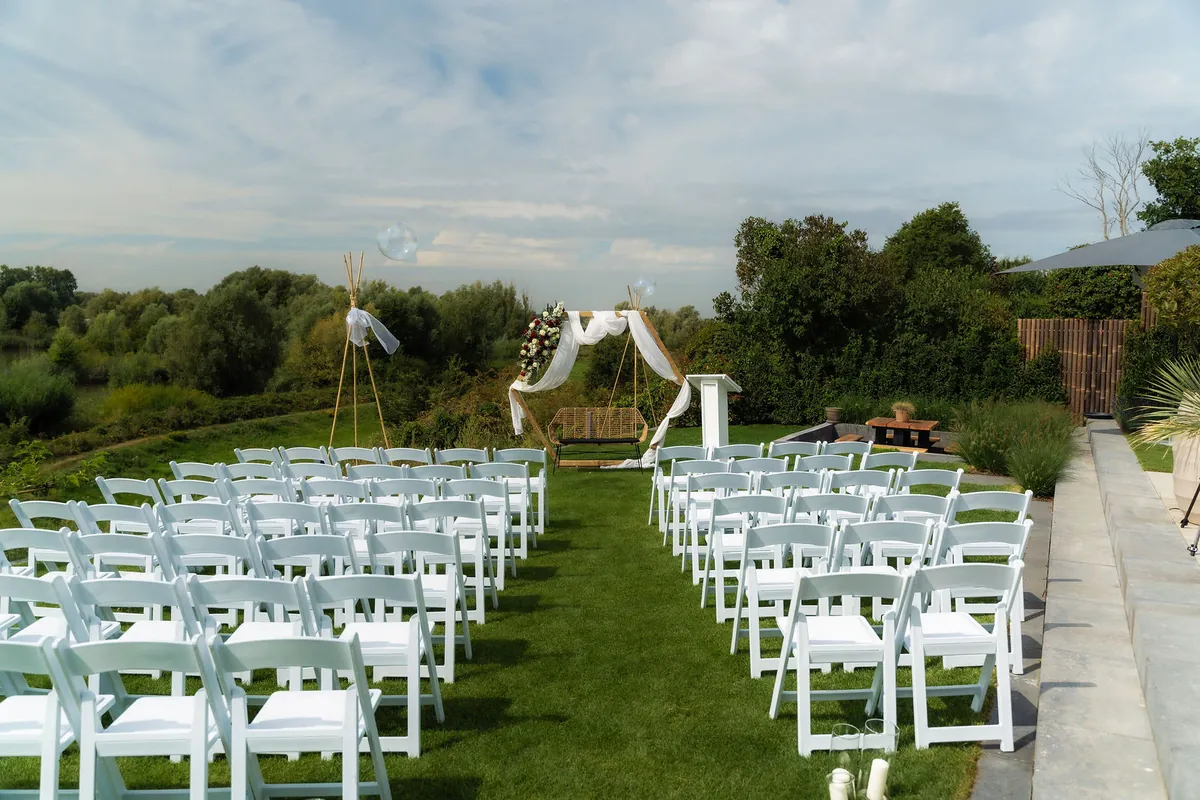 Witte stoelen en een boog voor de ceremonie, opgesteld op het gras
