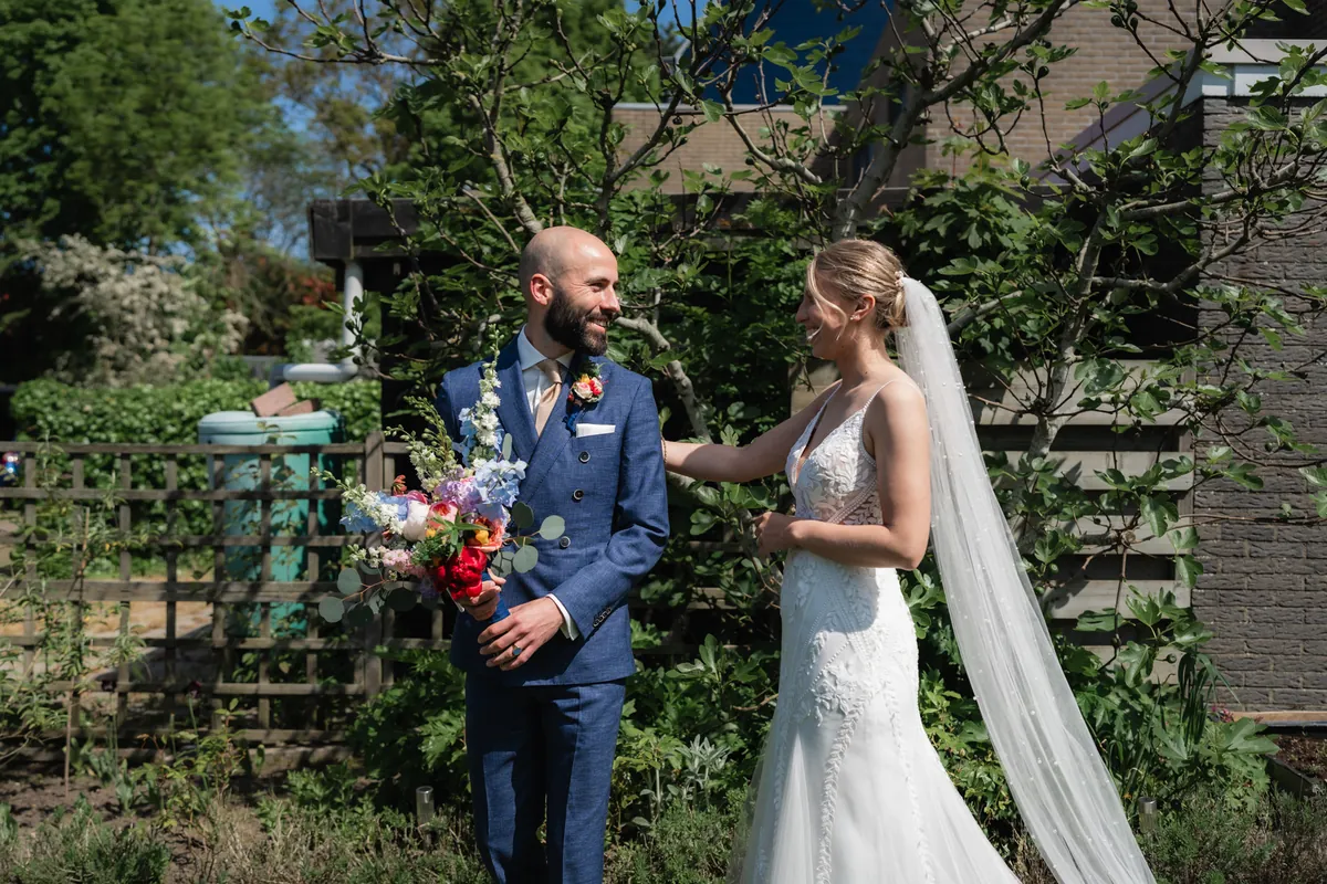 Bruidegom en bruid delen een first look in een sfeervolle tuin