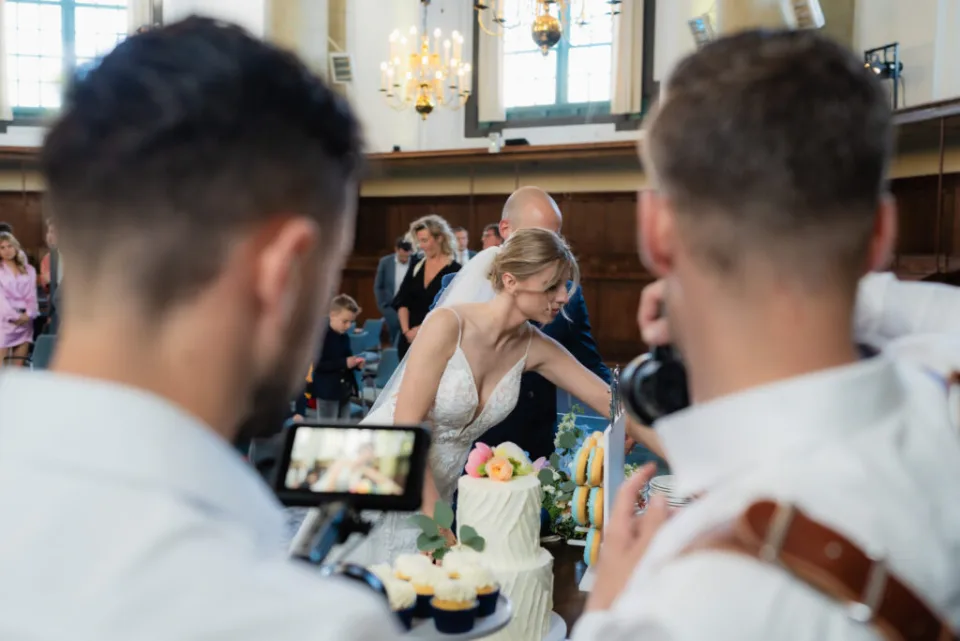 Videograaf Marco en een fotograaf van WeddingGuys leggen het aansnijden van de bruidstaart vast