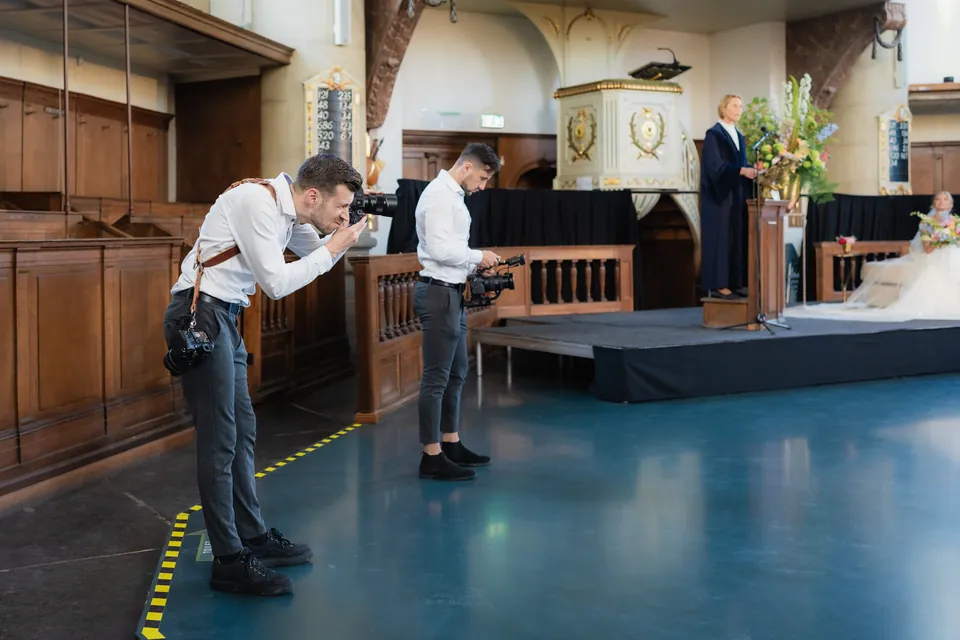 Videograaf Marco en een fotograaf van WeddingGuys leggen het bruidspaar vast tijdens de huwelijksceremonie