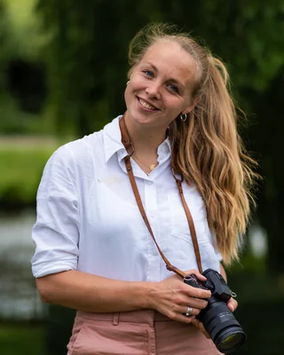 Ingrid van WeddingGuys met haar camera, buiten in het groen