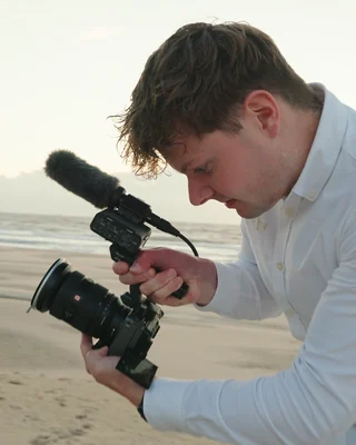 Niels van WeddingGuys filmt met een camera en microfoon aan zee